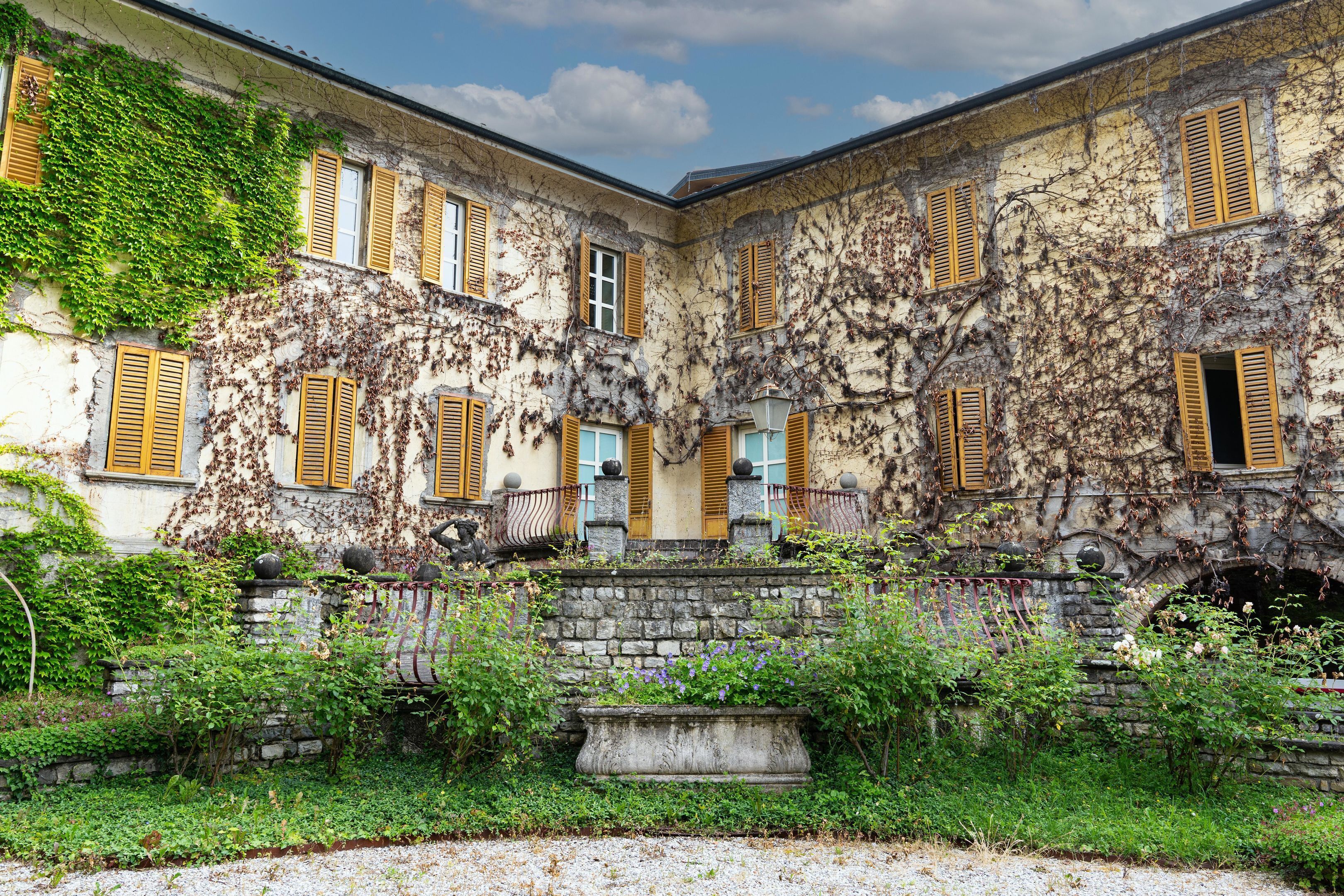 A historic building with ivy-covered walls, stone steps, and a small garden area.