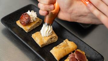 A person using a pastry bag to pipe cream onto a pastry.