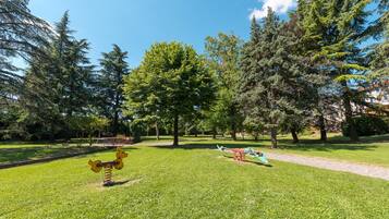 A park with green grass, trees, and playground equipment.