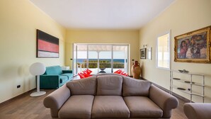 Ein Wohnzimmer mit großem Fenster, einer Couch, einem Couchtisch und einer Stehlampe.