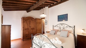 A bedroom with a metal bed frame, wooden wardrobe, and a tiled floor.
