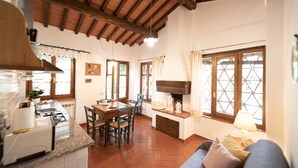 A kitchen with a dining table, chairs, a built-in oven, and a window with curtains.