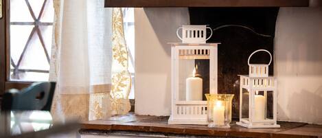 Une cheminée surmontée d’une étagère décorée de lanternes blanches et de bougies.