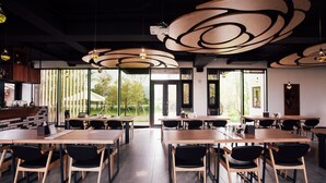 A modern restaurant with wooden tables and black chairs, large windows, and a unique ceiling design. - Villa Loherb (Dongshan)