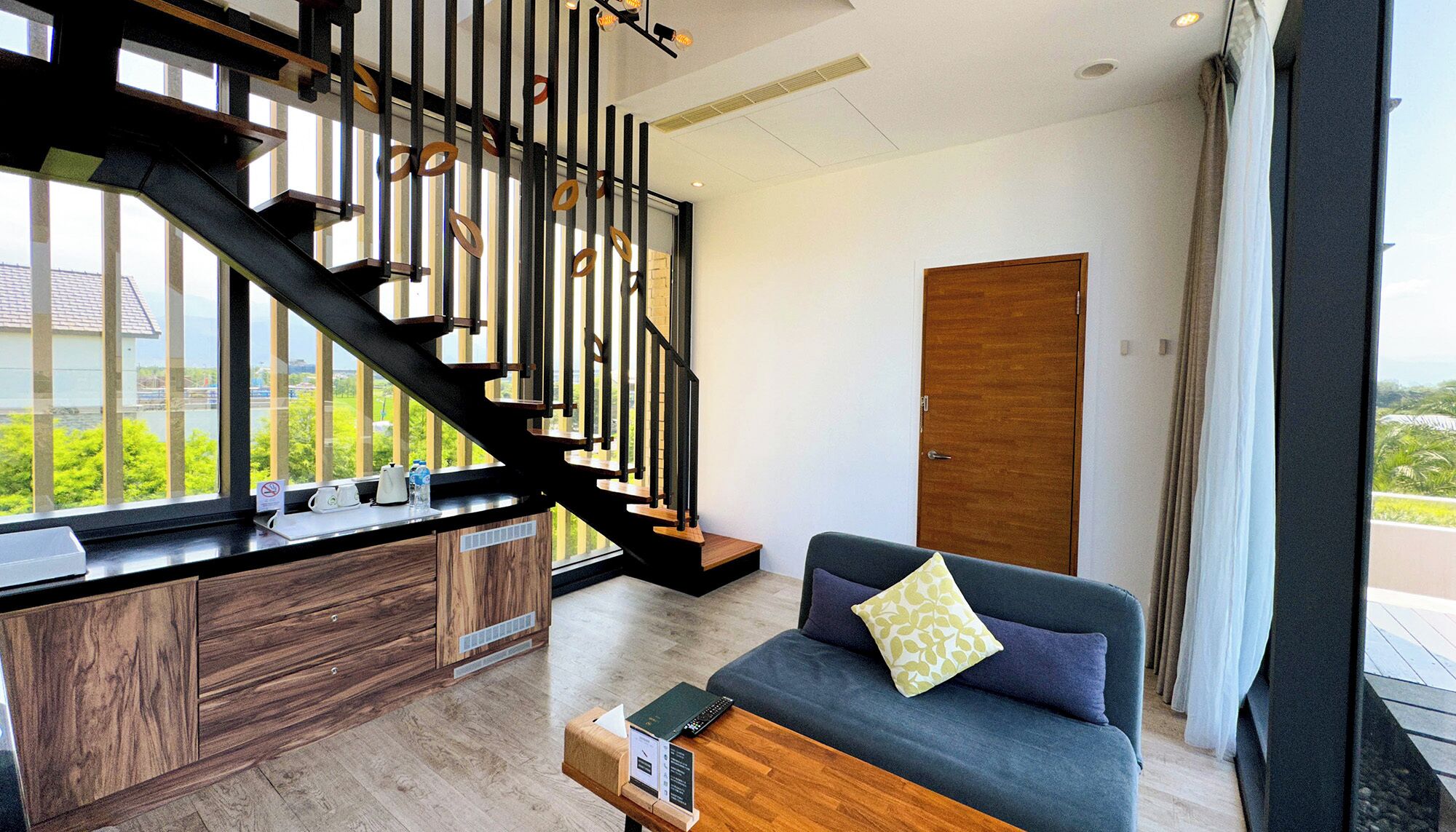 A modern living room with a staircase, a sofa, and a wooden cabinet.