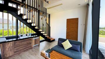 A modern living room with a staircase, a sofa, and a wooden cabinet.
