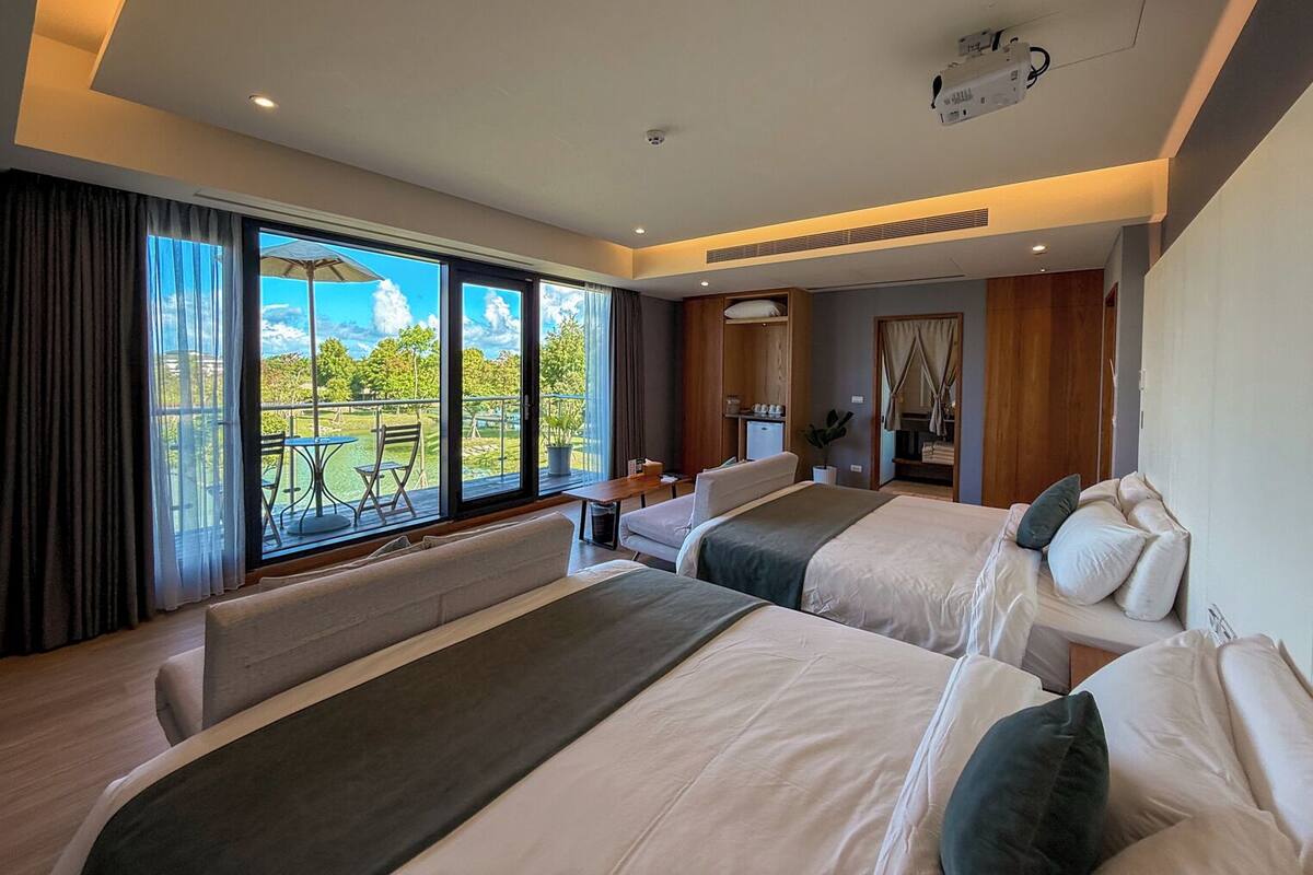Une chambre d’hôtel avec deux lits, un balcon et une vue sur l’extérieur.