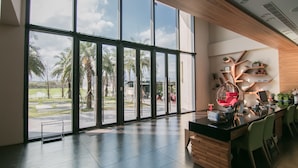 A modern interior with large windows, a wooden reception desk, and a view of palm trees. - Villa Loherb (Dongshan)