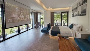 A modern hotel room with a large bed, a sofa, a coffee table, and a TV screen displaying a program. - Villa Loherb (Dongshan)