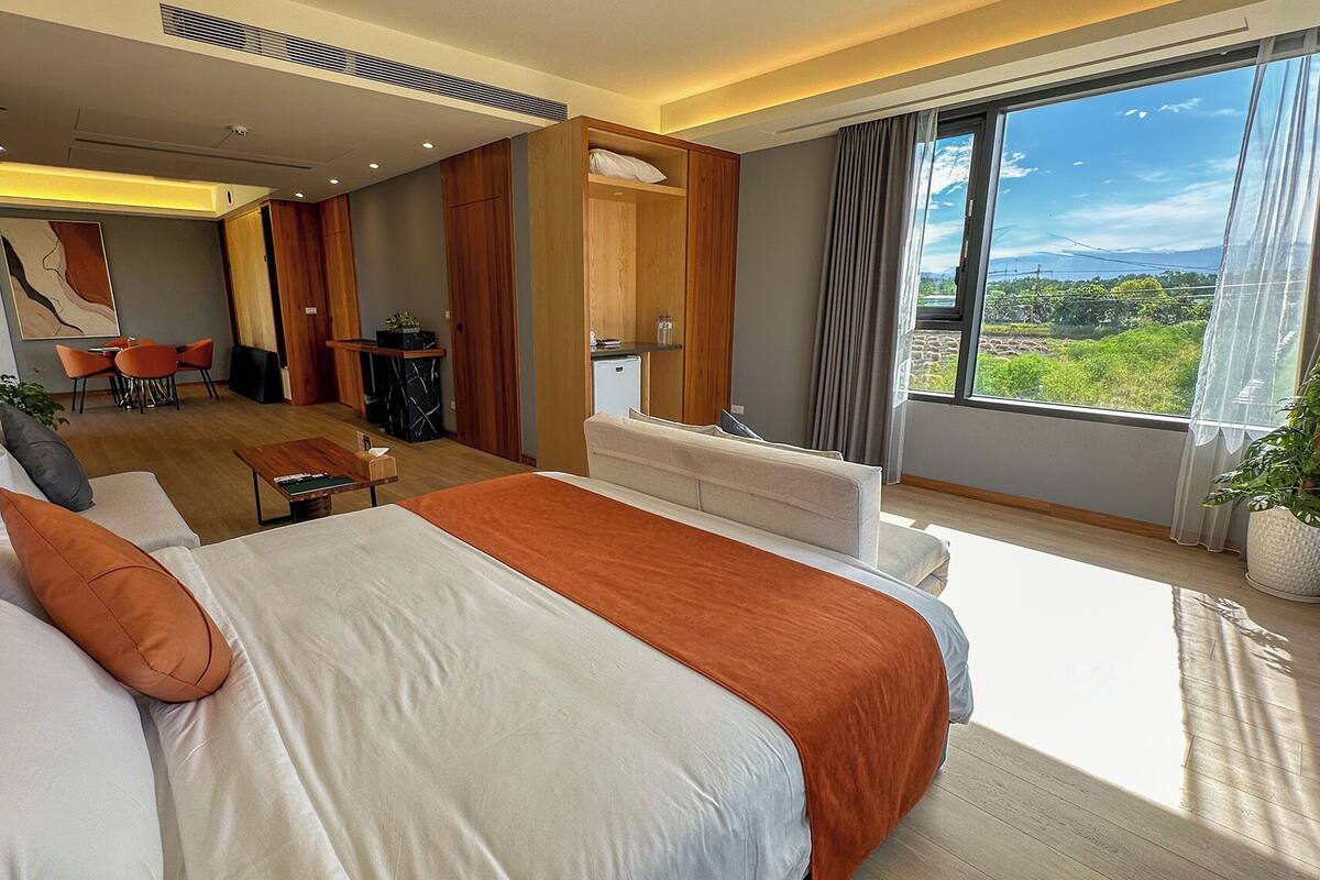 Une chambre d’hôtel moderne dotée d’un grand lit, d’un coin salon et offrant une vue sur l’extérieur.