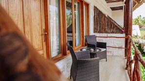 A balcony with wicker furniture, wooden doors, and a view of the outdoors. - Tamani Villas Annex (Matemwe)
