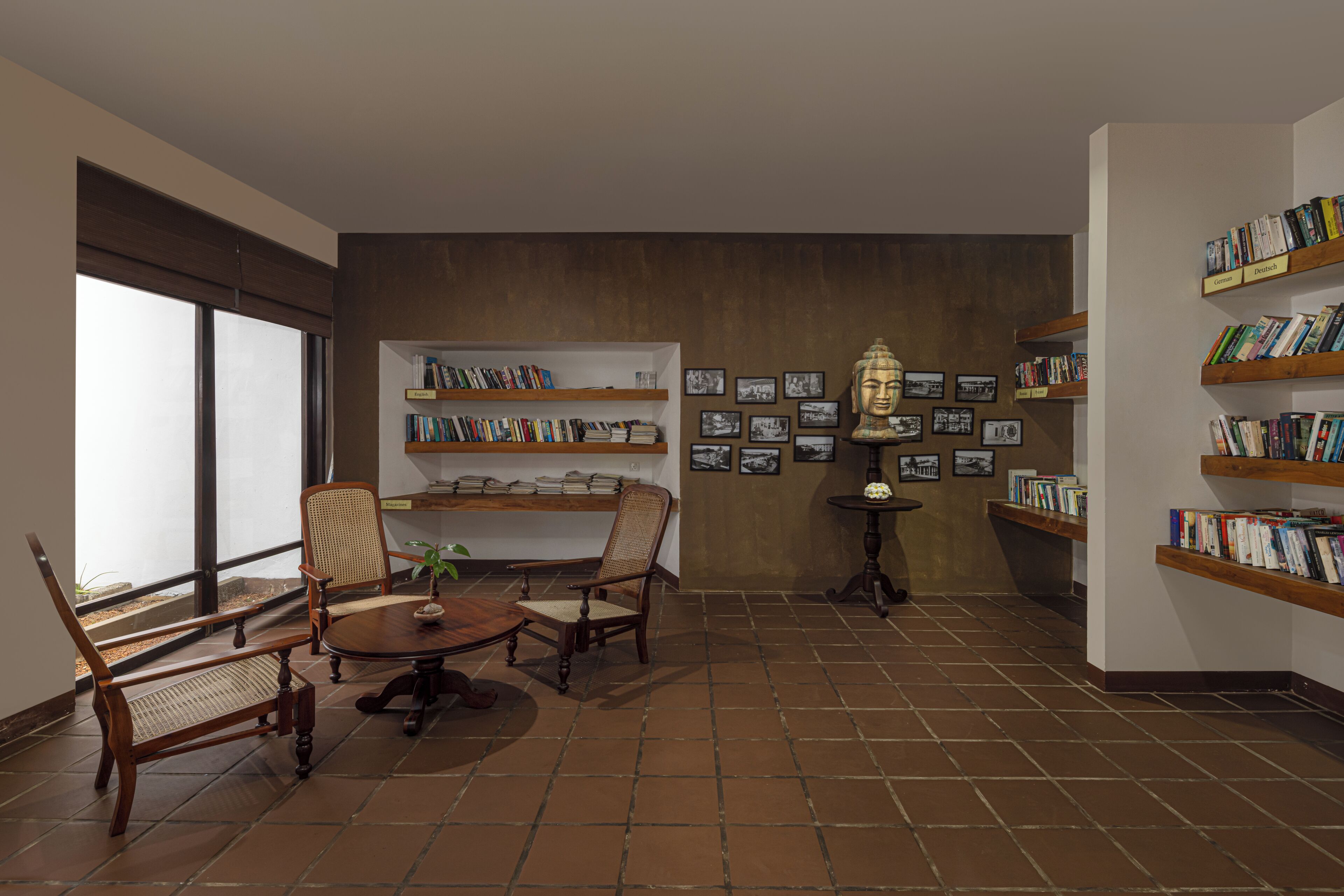 Une bibliothèque avec des étagères, une table ronde, des chaises et des tableaux encadrés accrochés au mur.