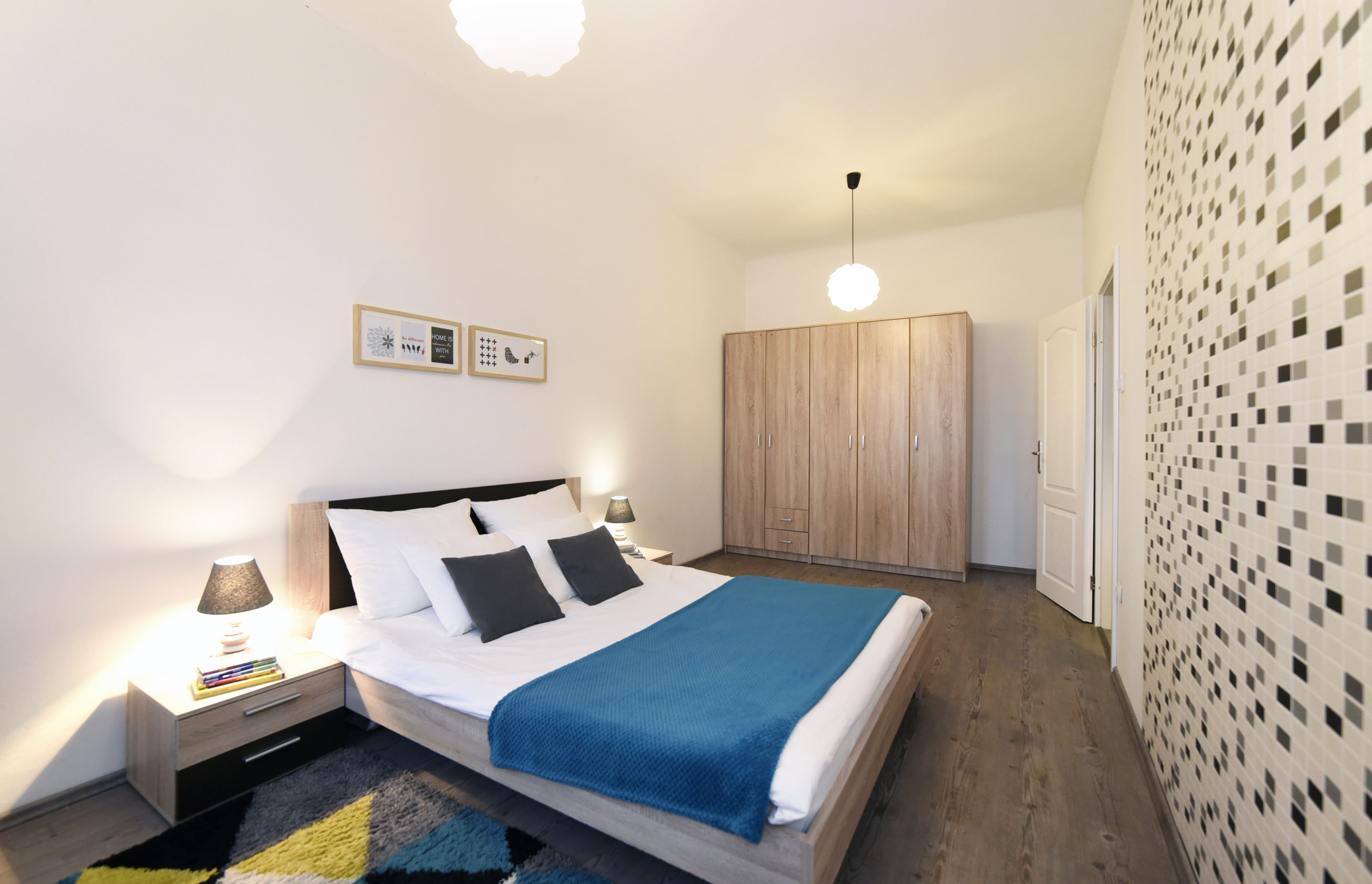 Une chambre à coucher comprenant un lit, des tables de chevet, une armoire et un mur orné d’un motif en mosaïque.
