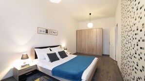 Een slaapkamer met een bed, nachtkastjes, een kledingkast en een muur met een mozaïekpatroon.