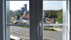 Uitzicht door een raam op een stadsgezicht, met gebouwen en een weg.
