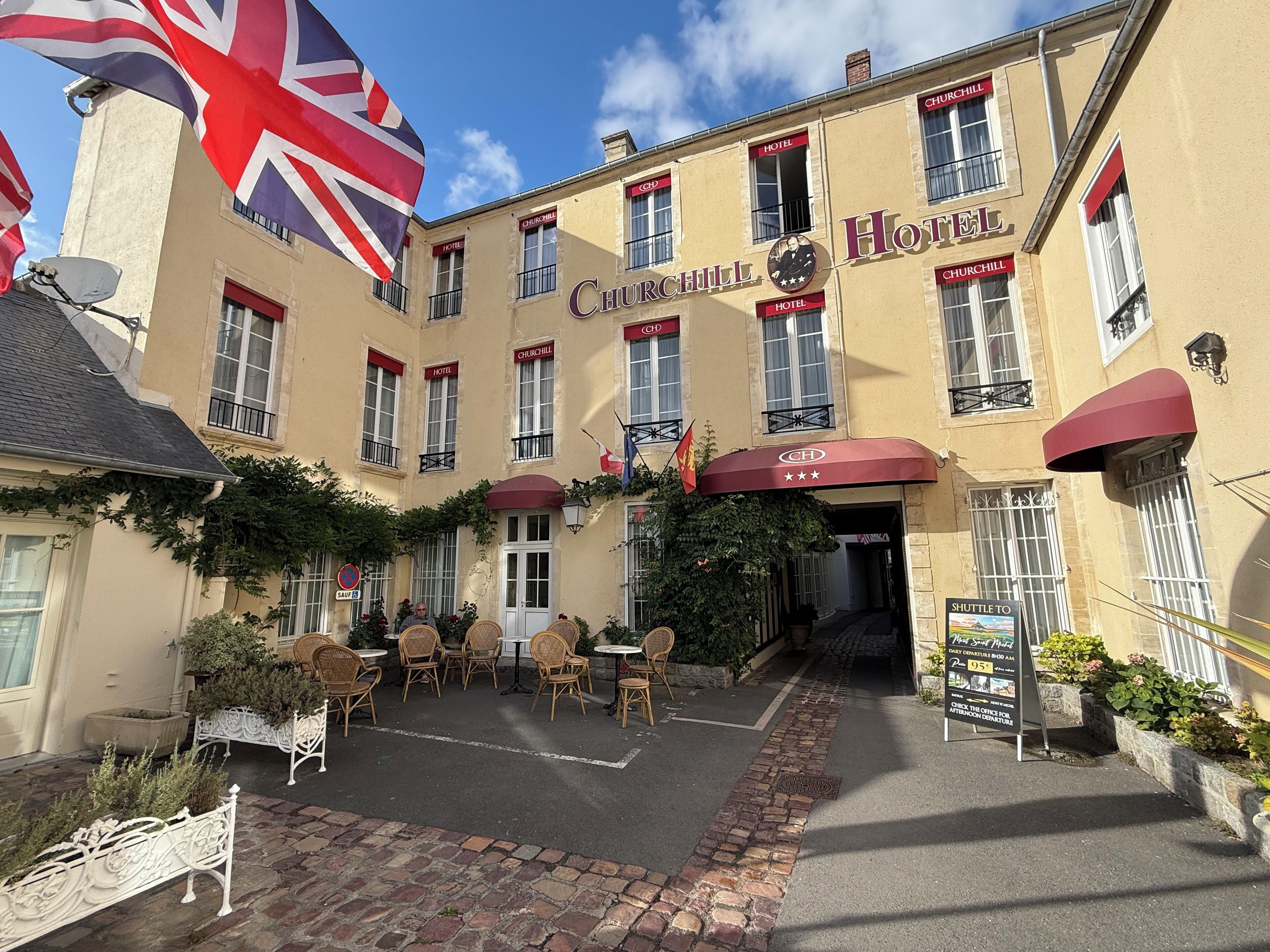 Churchill Hotel with a red awning, outdoor seating, and a British flag.
