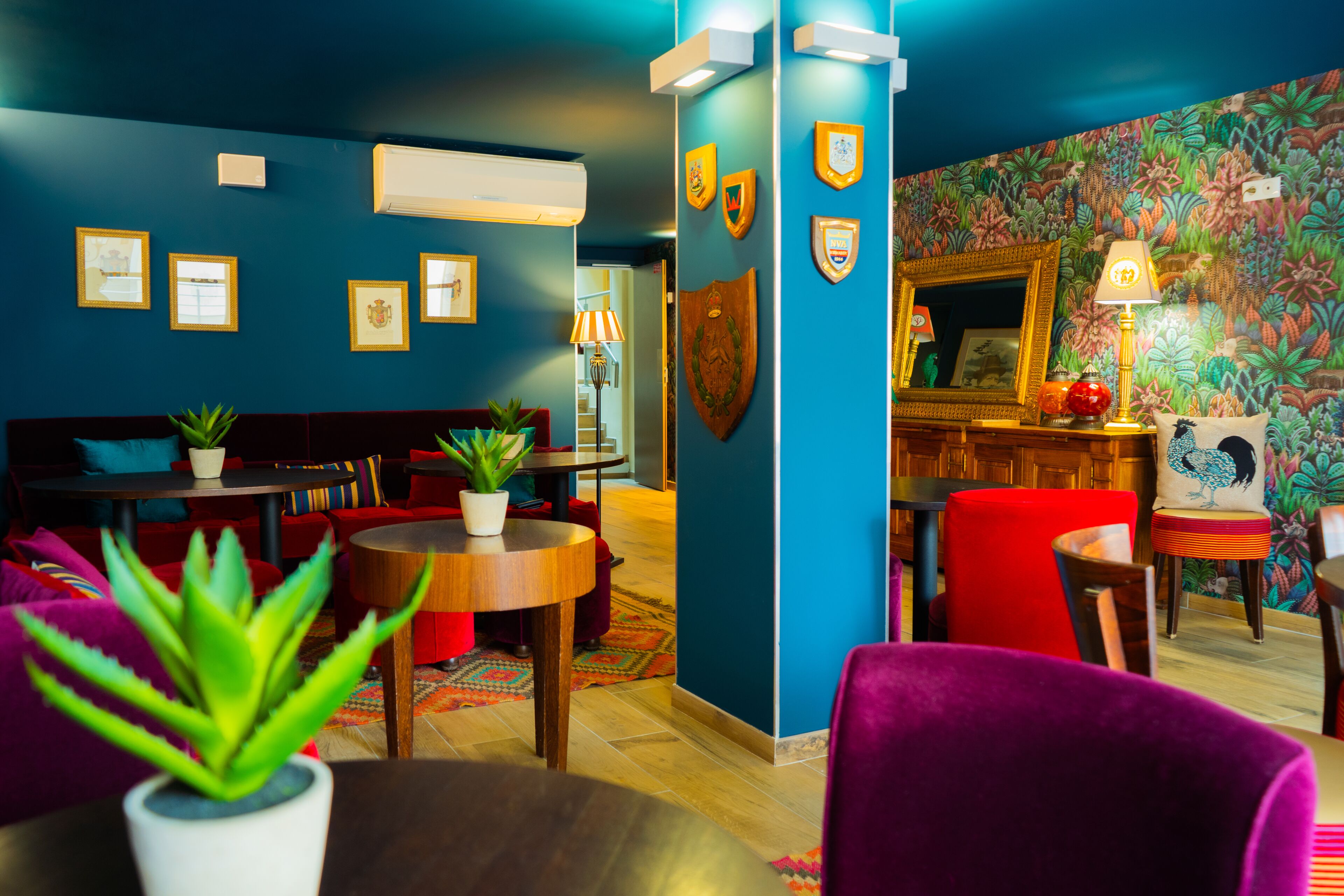 A room with a blue wall, wooden furniture, and a colorful floral wallpaper.