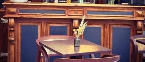 Una zona de bar con paneles de madera, una variedad de botellas y un florero con flores.