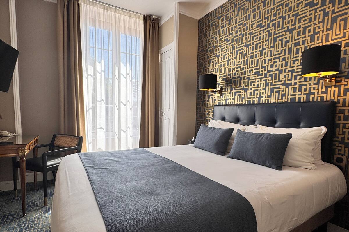 A hotel room with a large bed, a desk, and a chair.
