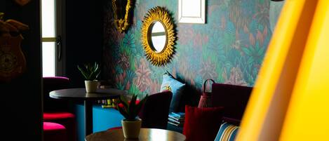 A room with a round table, red chairs, a potted plant, and a mirror on the wall.