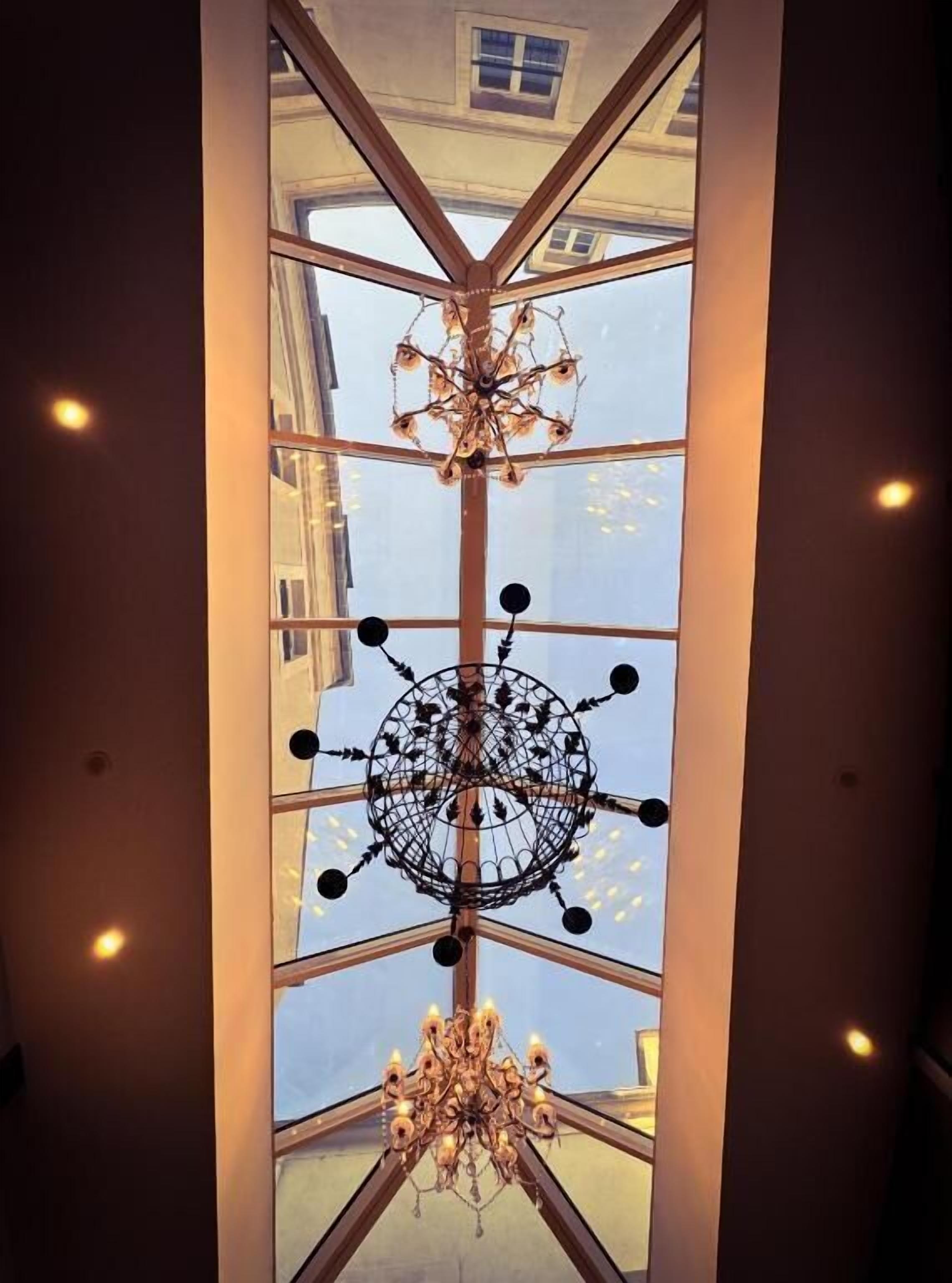 A room with a large skylight, a chandelier, and a window with a view of the sky.
