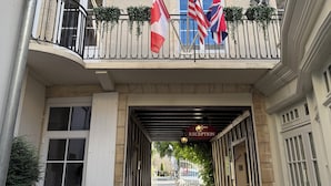 A hotel entrance with a reception sign, flags, and a cobblestone pathway.