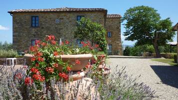 Un bâtiment en pierre avec un toit en tuiles, entouré de gravier et de plantes de lavande.