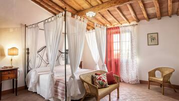 Une chambre à coucher avec un lit à baldaquin, une chaise en osier, une table de chevet et un rideau rouge.
