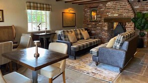 Una sala de estar acogedora con chimenea de ladrillo, un conjunto de sofás y un comedor con mesa y sillas.