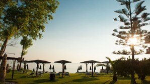 A beachside resort with sun loungers, umbrellas, and a clear view of the ocean. - Zarkadis Beach Apartments (Zakynthos)