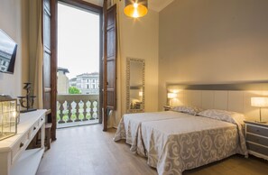 A hotel room with a large bed, bedside tables, a mirror, and a view of the city through an open door. - Iris Apartments by Mmega (Florence)