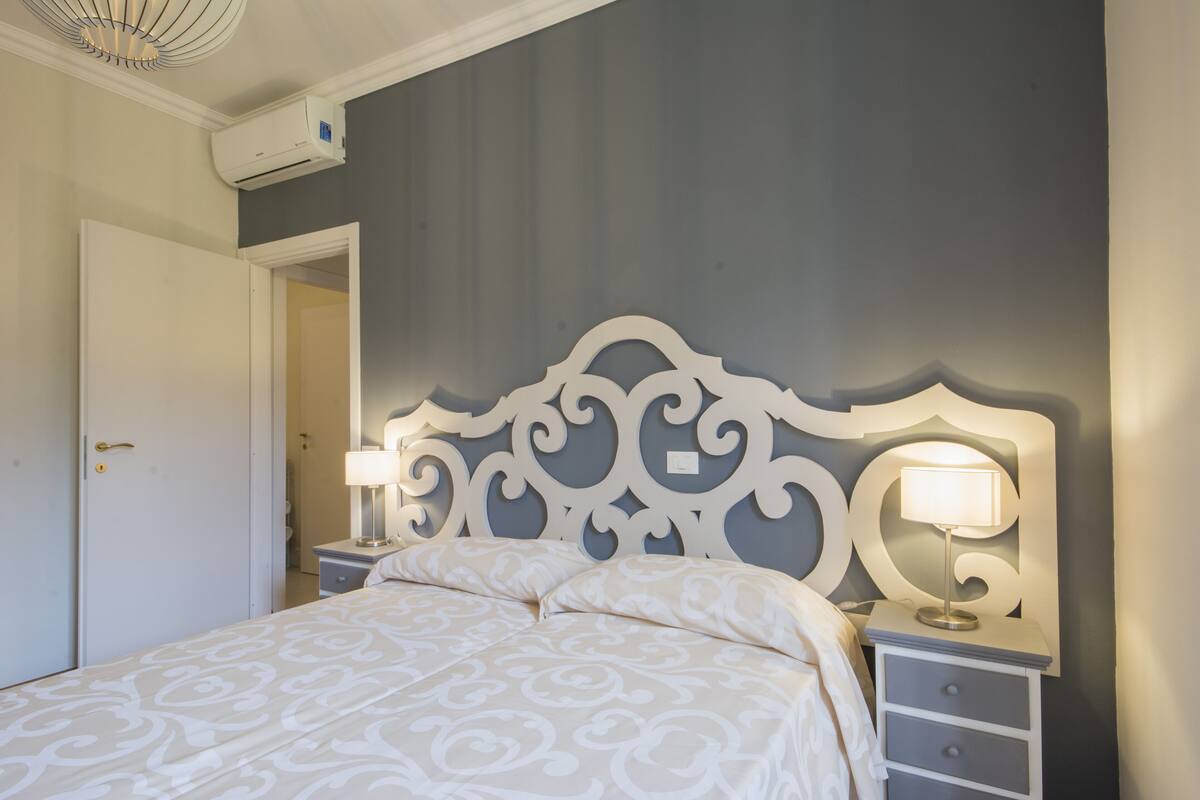Une chambre à coucher avec un lit, une table de chevet, une lampe et une porte.