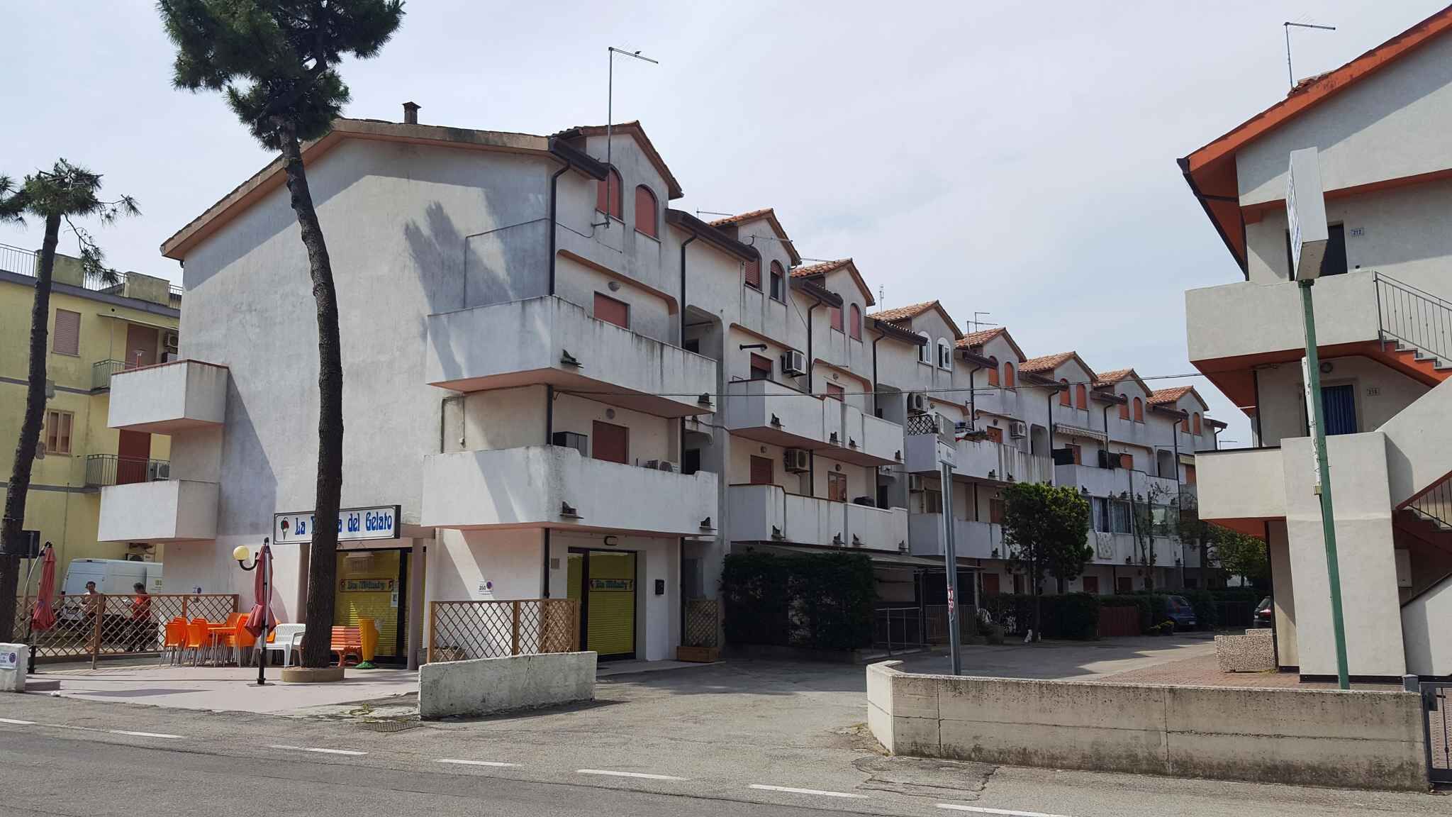 Un immeuble résidentiel à plusieurs étages, doté de balcons, d’une entrée au niveau du sol et d’une devanture visible.