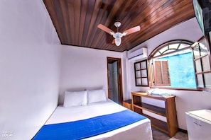 Ein Schlafzimmer mit Bett, Schreibtisch und Fenster.