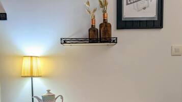 Een eetruimte met een marmeren tafel, een rieten stoel, een lamp en een ingelijst poster aan de muur.