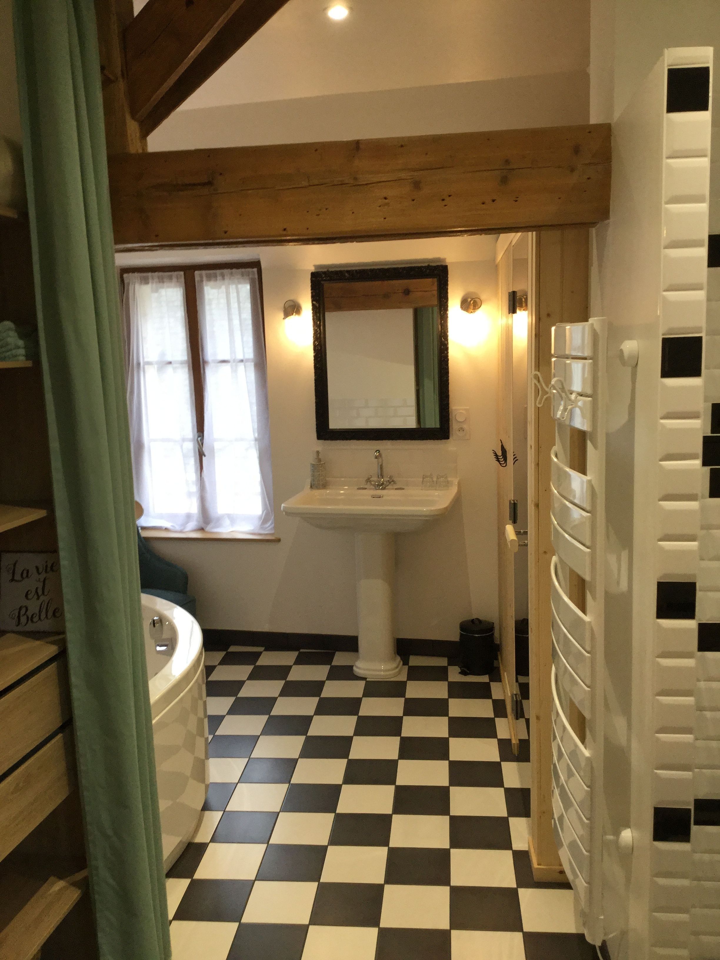 A bathroom with a checkered floor, a sink, a mirror, and a bathtub.