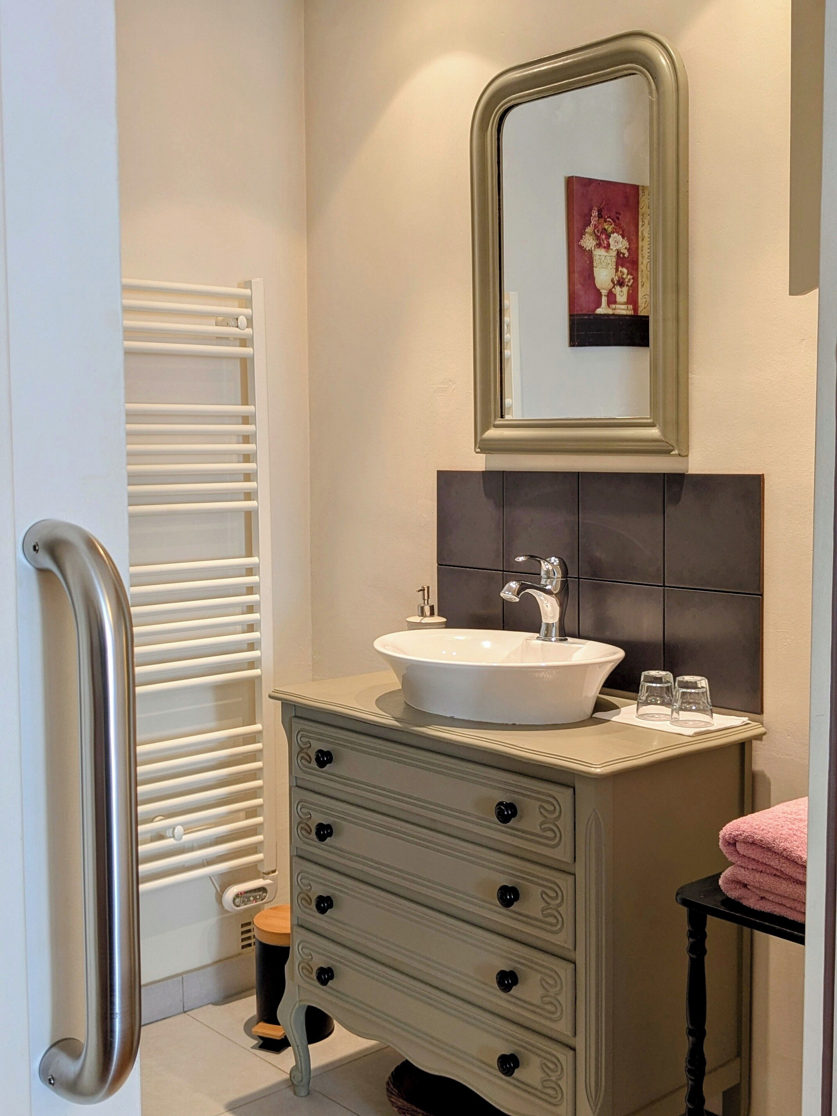 A bathroom with a white sink, a mirror above it, and a towel rack.