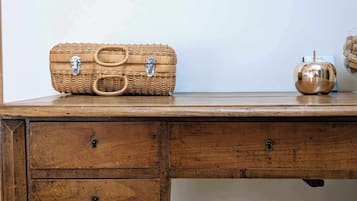 A wooden desk with a wicker basket, a small metal object, and a fur-covered stool.