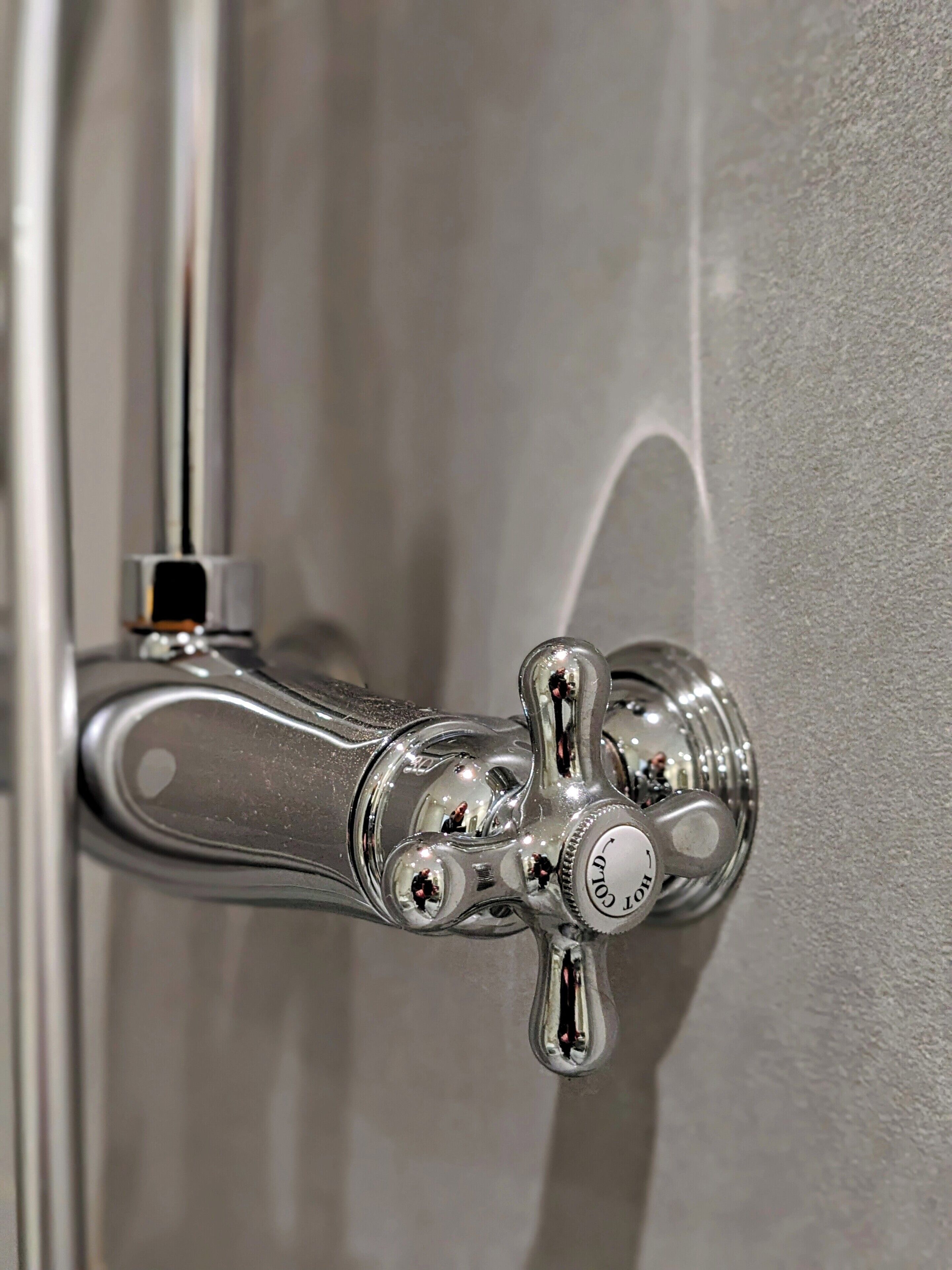 Un baño con una llave de cromo fijada en la pared.