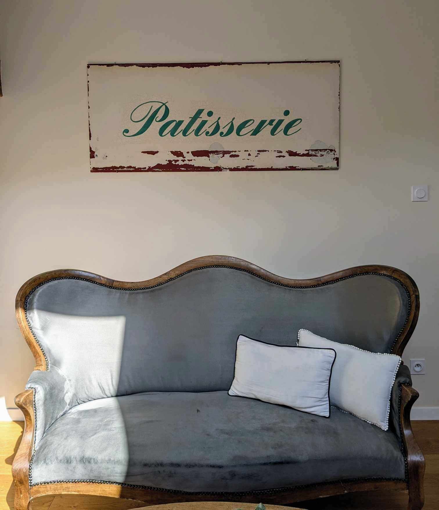A vintage-style sofa with a cushion and a sign above it that reads "Patisserie".