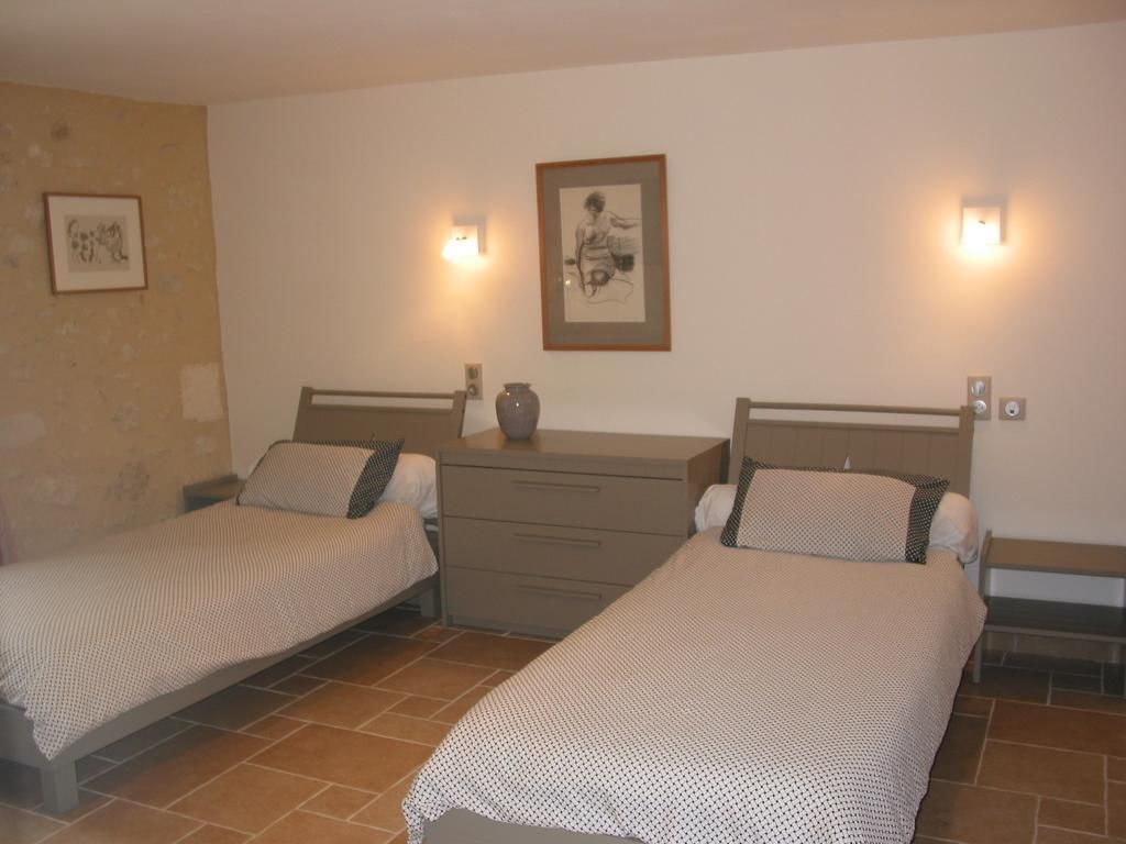 Una habitació amb dos llits individuals, una nit falda amb un ram i un quadre al mur.