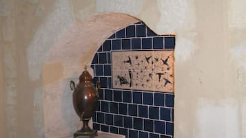 A stone wall with a tiled section featuring a bird and floral design.