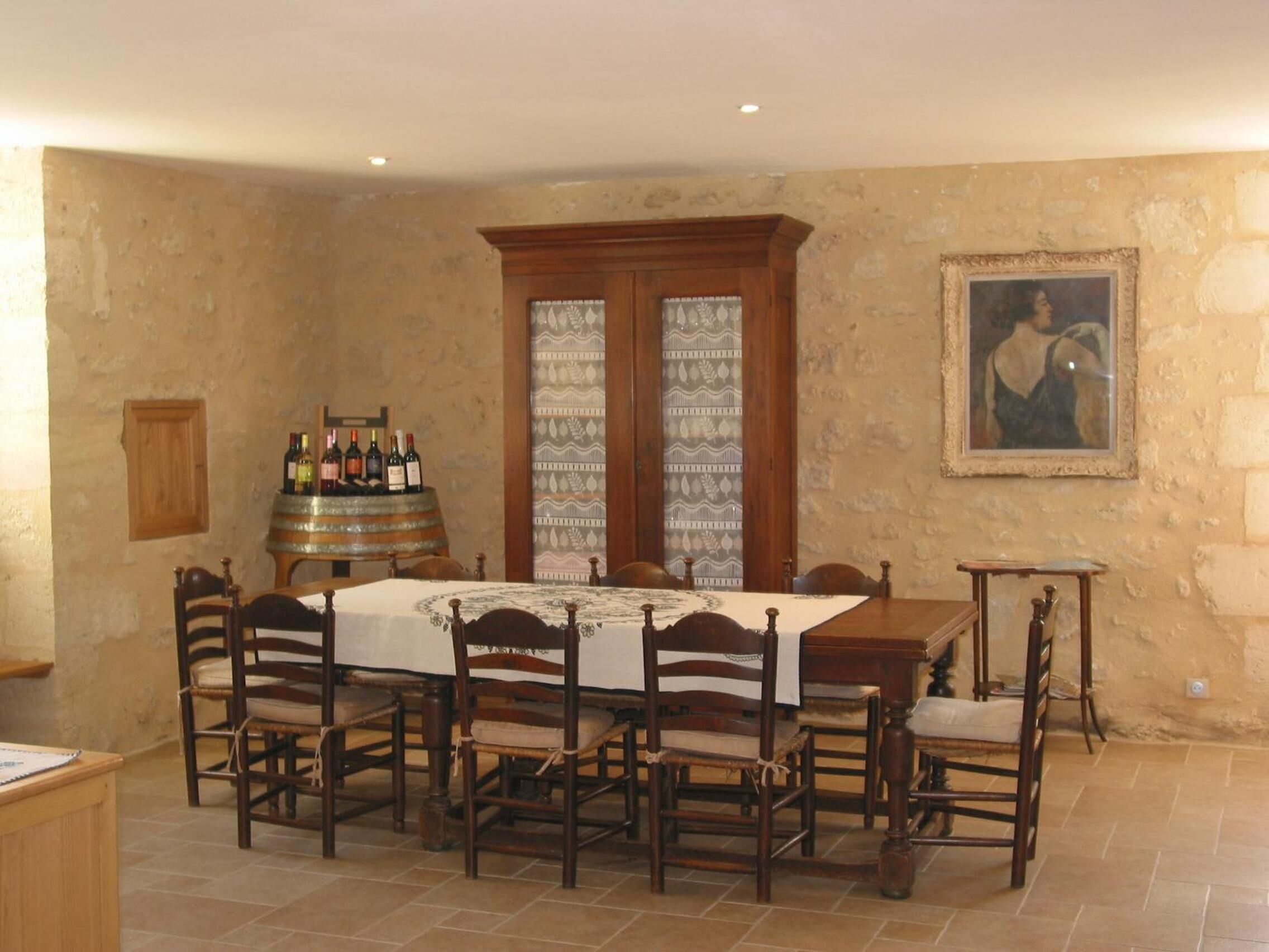 Comedor con mesa de madera, sillas, un barril de vino y un cuadro en la pared.