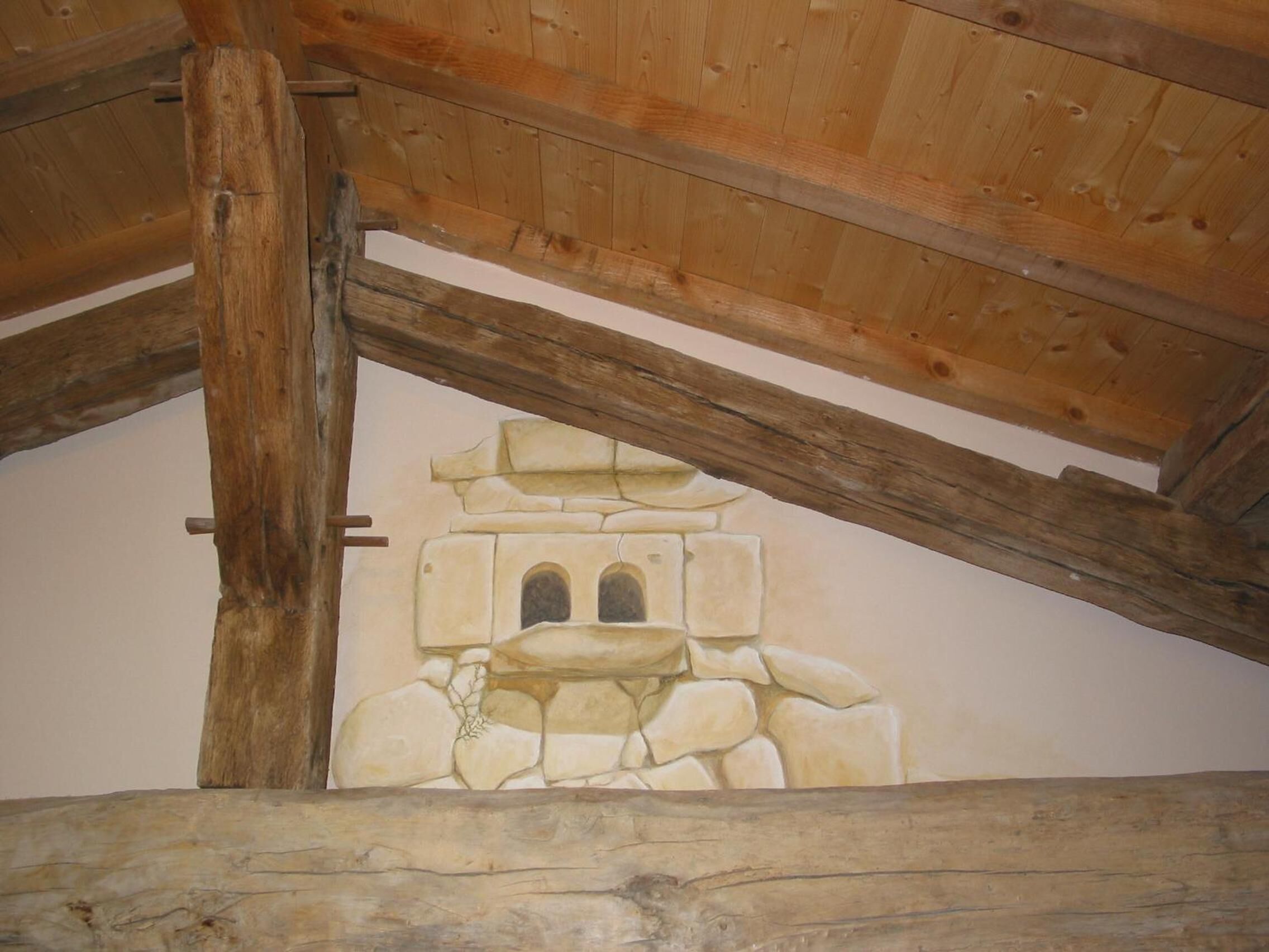 A rustic wooden ceiling with exposed beams and a stone wall mural.