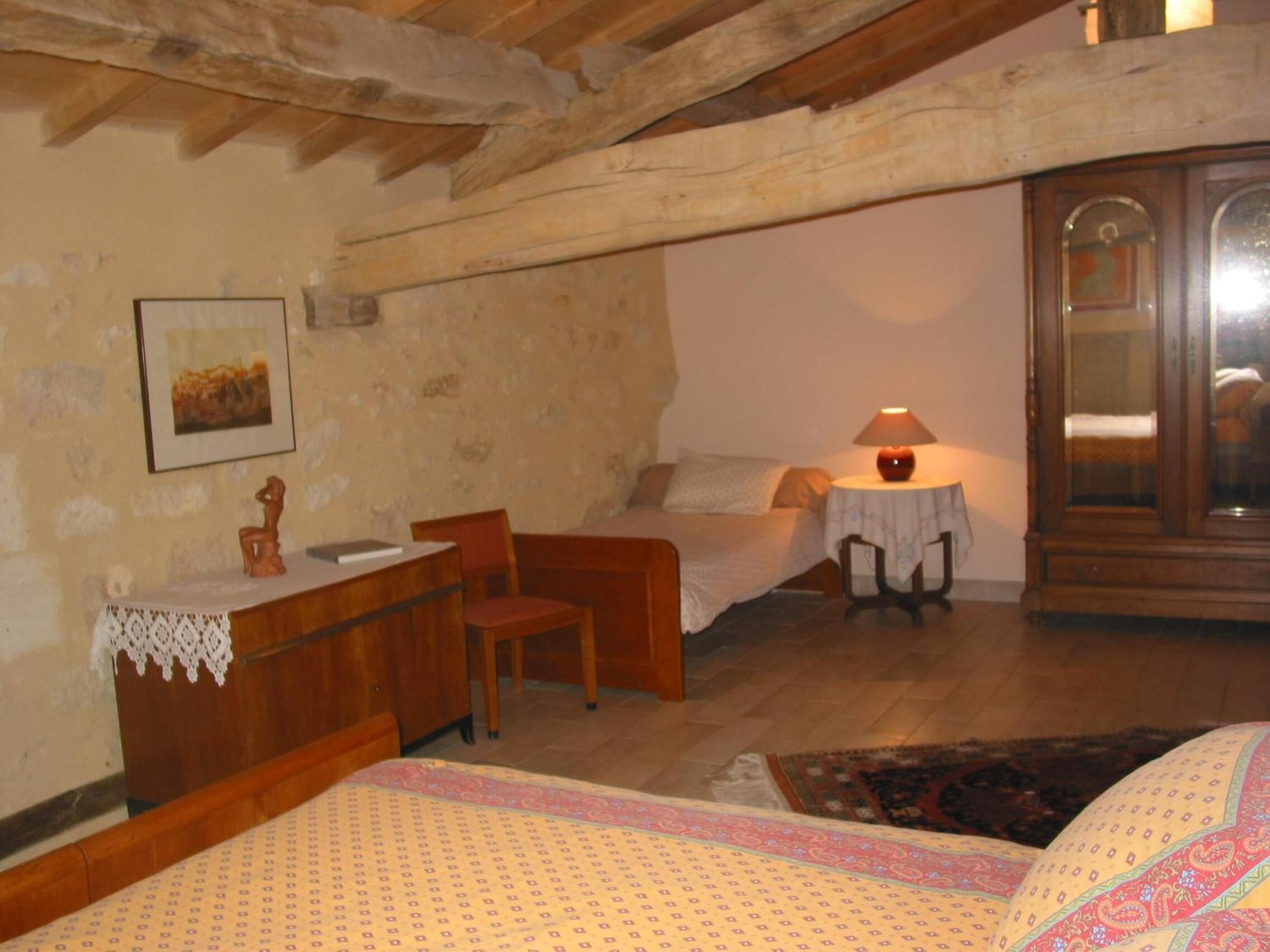 Una habitación acogedora con cama, un escritorio pequeño, una silla y una mesa con lámpara.