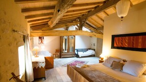 Un dormitorio con techo de madera, cama, mesita de noche, silla y cómoda.