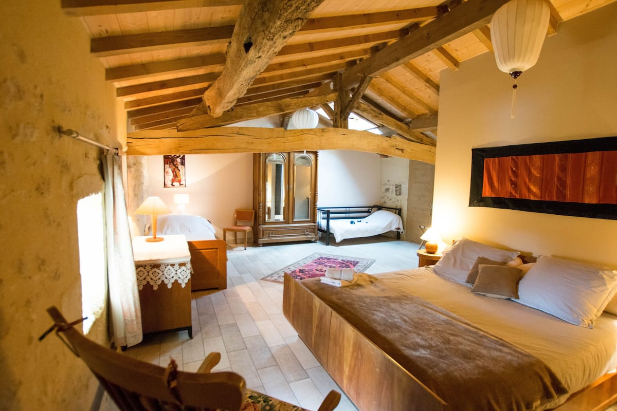 Un dormitorio con techo de madera, cama, mesita de noche, silla y cómoda.