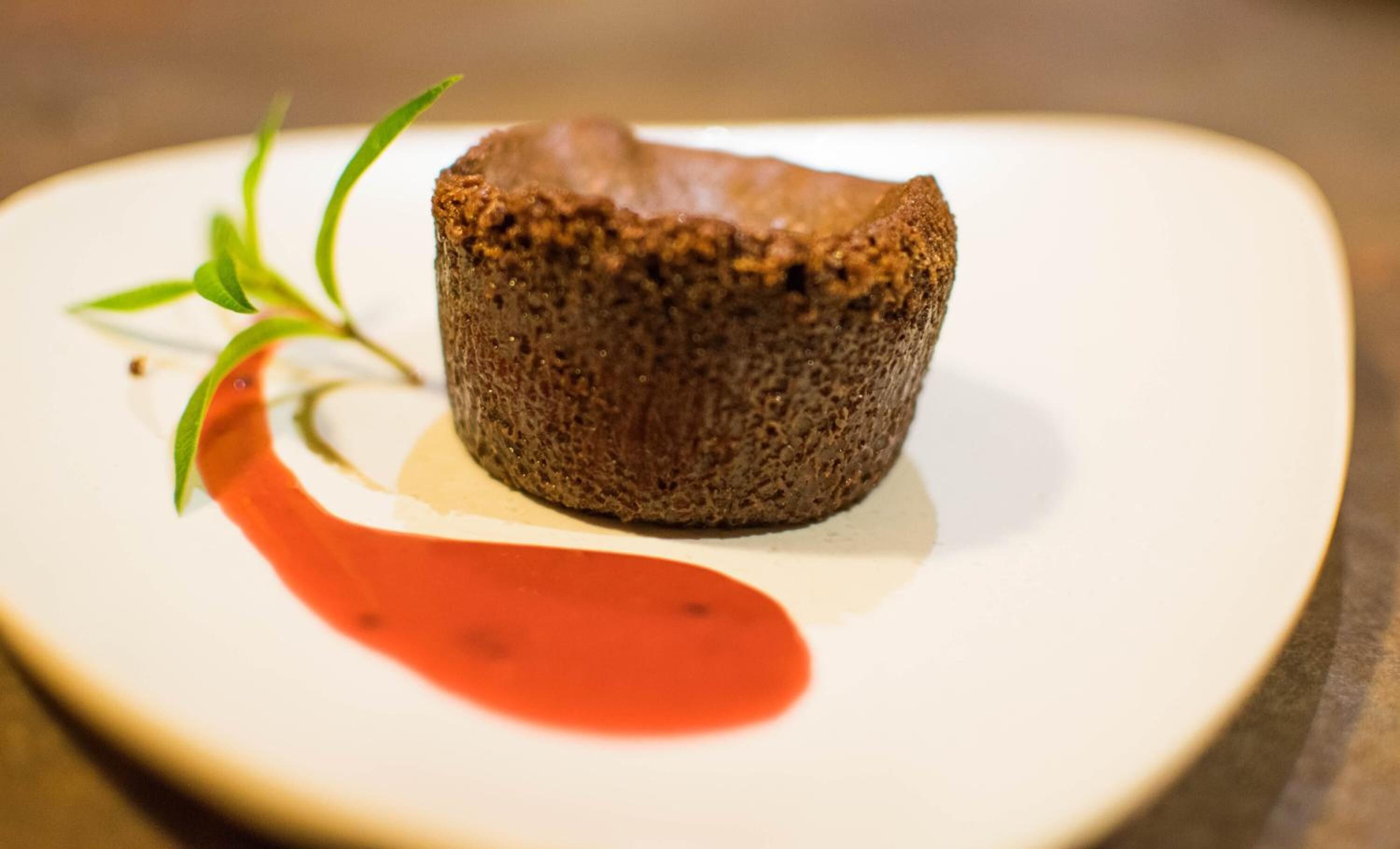 A dessert on a white plate with a red sauce and green garnish.