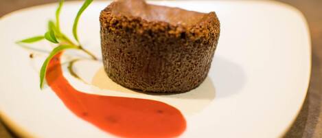 A dessert on a white plate with a red sauce and green garnish.