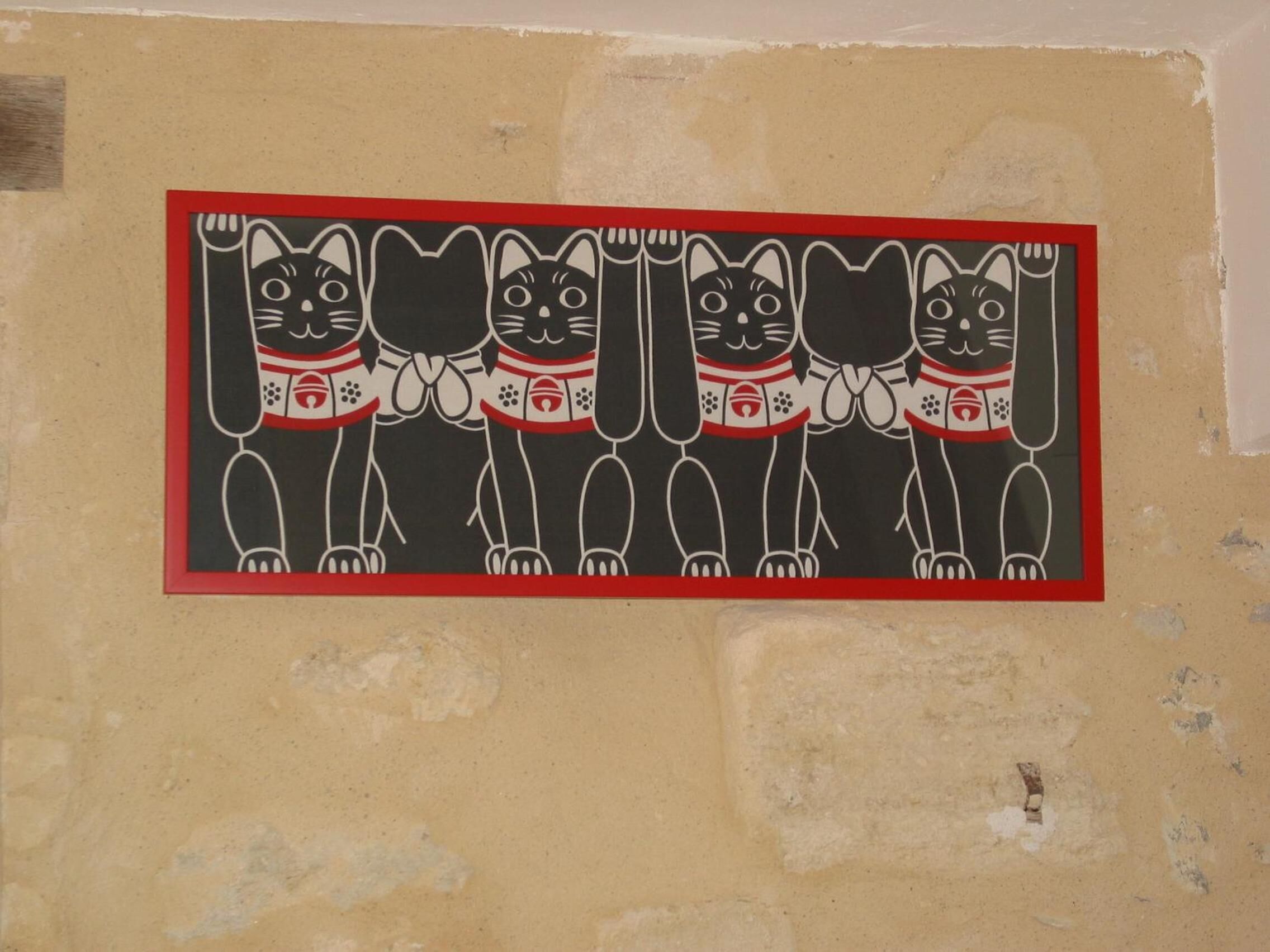A wall with a framed artwork of four stylized cats.